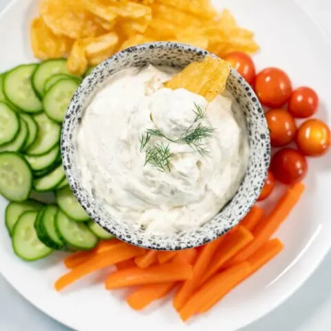 Closeup on a small bowl of Dill Dip with chips.