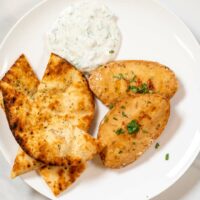 Top view of a white plate with a portion of Tandoori Chicken with Naan.