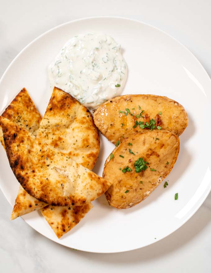 Top view of a white plate with a portion of Tandoori Chicken with Naan.