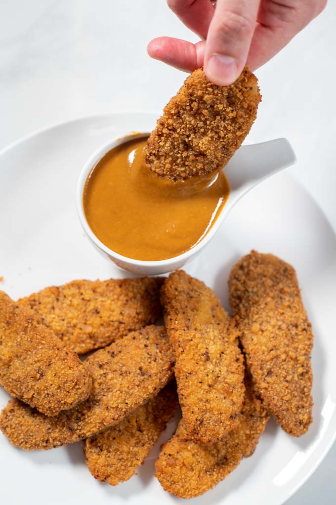 Dipping chicken tenders into Carolina BBQ Sauce.