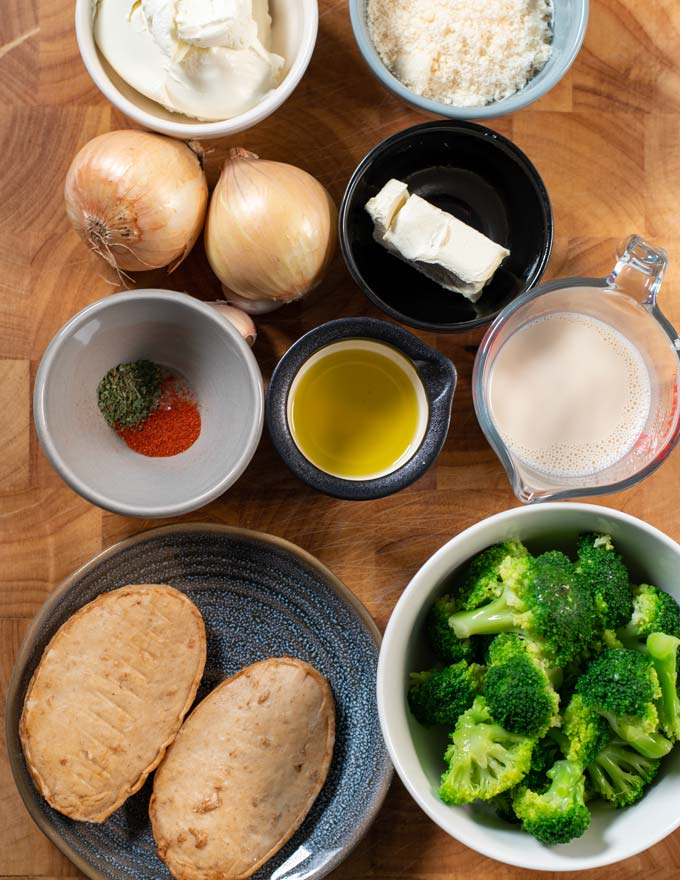 Ingredients for making Chicken Broccoli Alfredo are collected on a board.