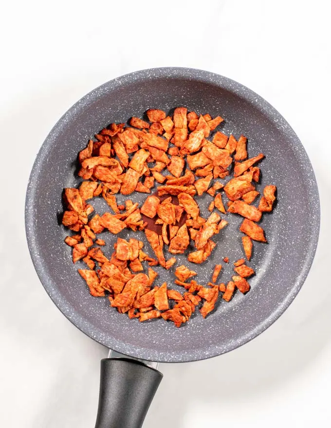 View of a pan with vegan bacon being fried.