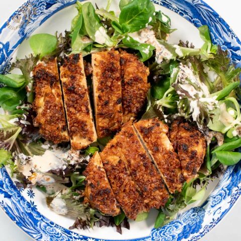 Top view of a serving plate of Crispy Chicken on top of salad.