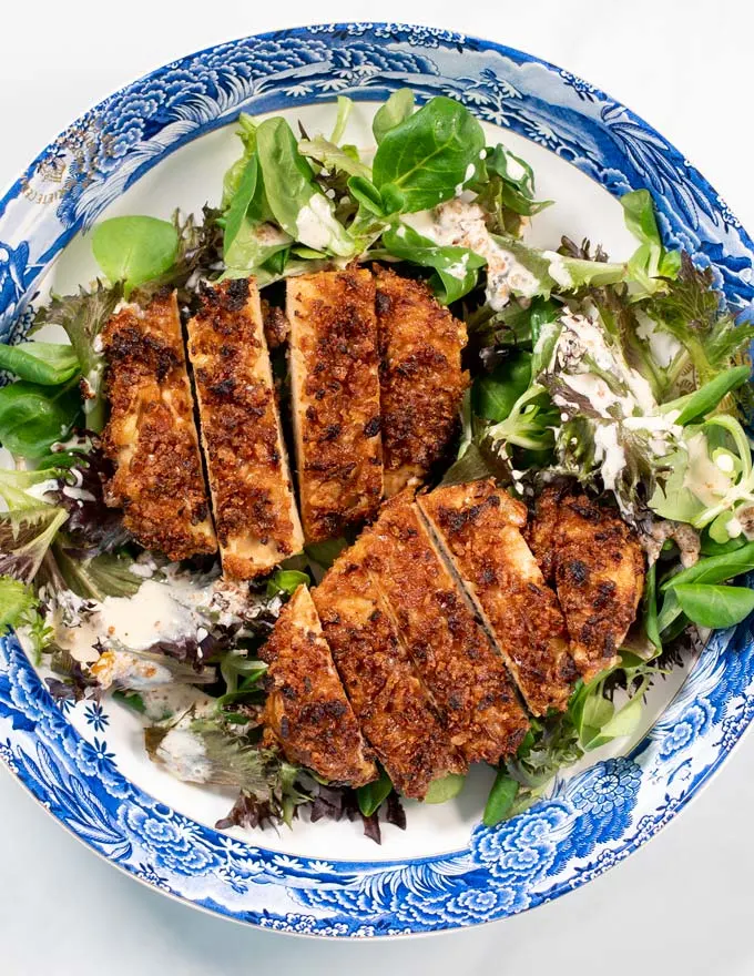 Top view of a serving plate of Crispy Chicken on top of salad.