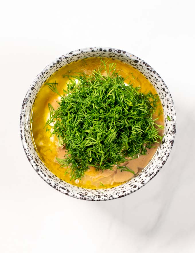 Fresh dill is given to the mixing bowl with the liquid ingredients of the Dill Sauce.