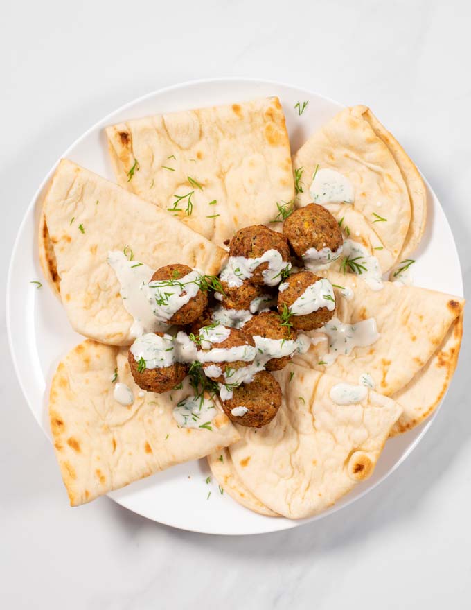 Serving of a plate of falafel with bread dressed with Dill Sauce.