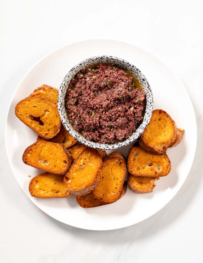 Top view of a serving plate of Olive Tapenade with crusty bread.