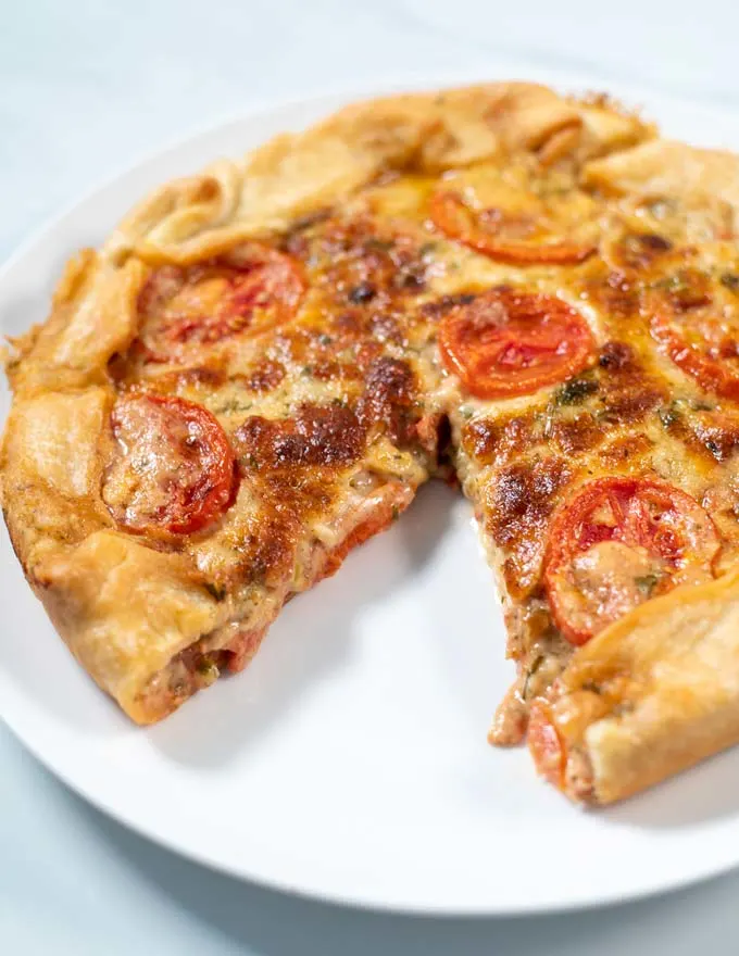 Tomato Pie with a missing piece on a white serving plate.