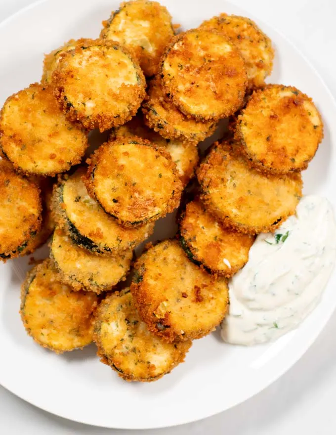 A plate with Fried Zucchini and dipping sauce.