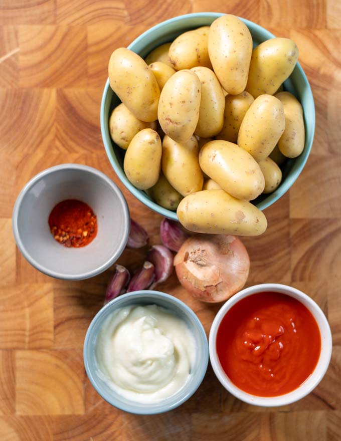 Ingredients needed to make Patatas Bravas are collected on a cutting board.