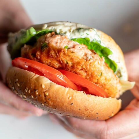 Salmon Burger is held in hands.