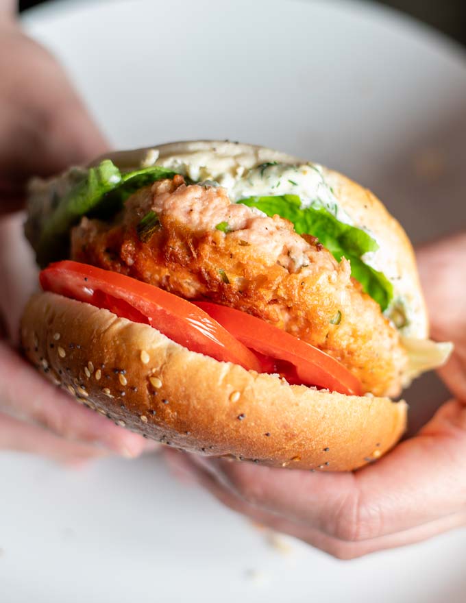 Salmon Burger is held in hands.