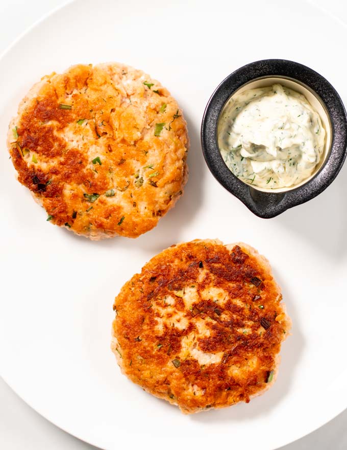 Two golden-brown cooked Salmon Burger patties.