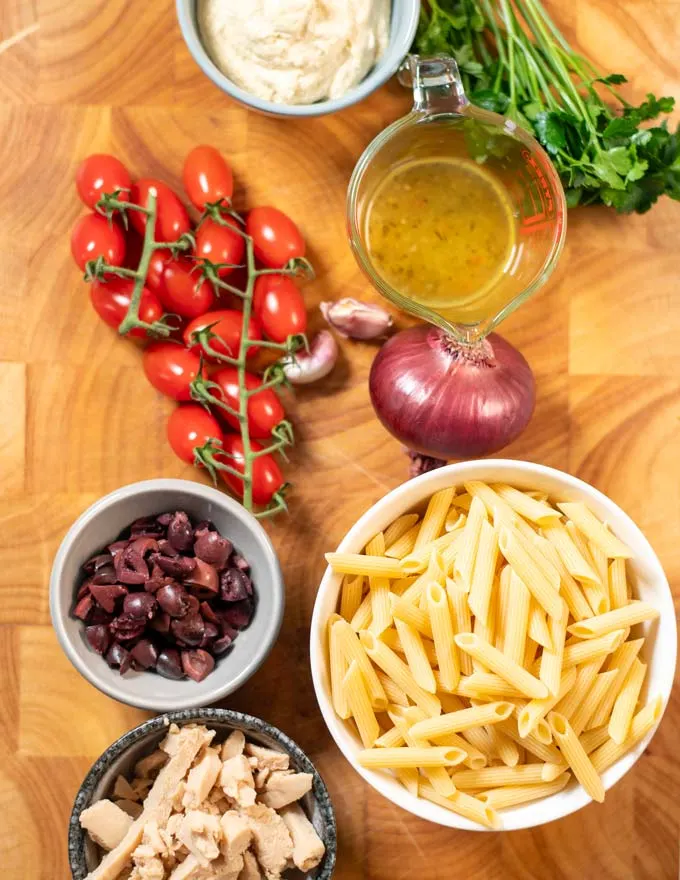 Ingredients needed for making Chicken Pasta Salad are collected on a board.