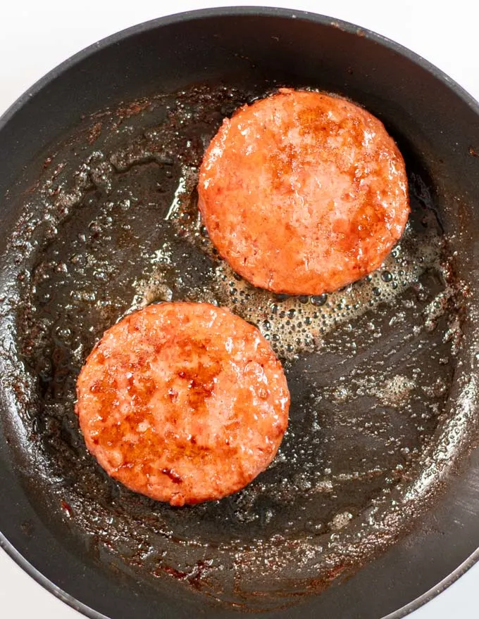 Top view of a frying pan with two burgers.