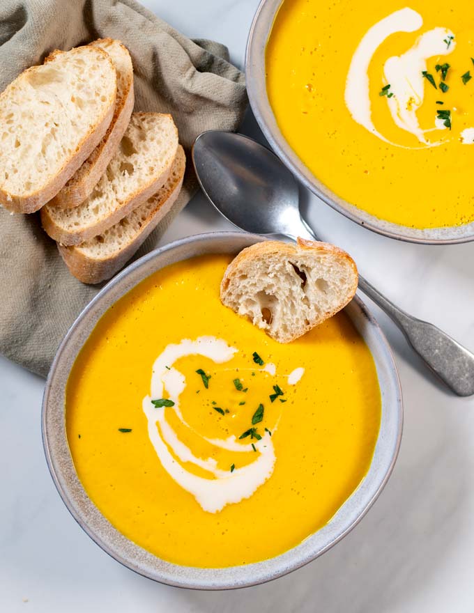 A slice of bread is dunked into Pumpkin Soup.