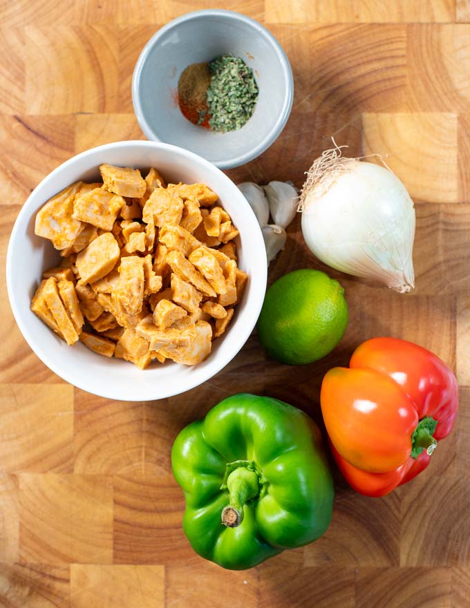 Ingredients needed to make vegan Chicken Fajitas are collected on a board.