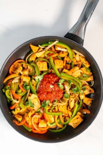 Fresh salsa is given into the pan with Chicken Fajitas.