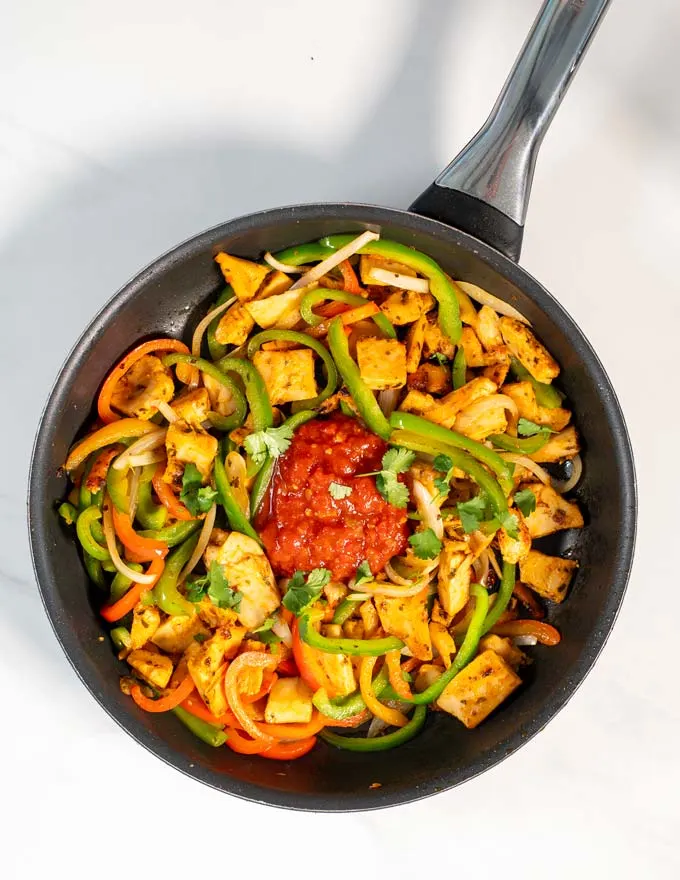 Fresh salsa is given into the pan with Chicken Fajitas.