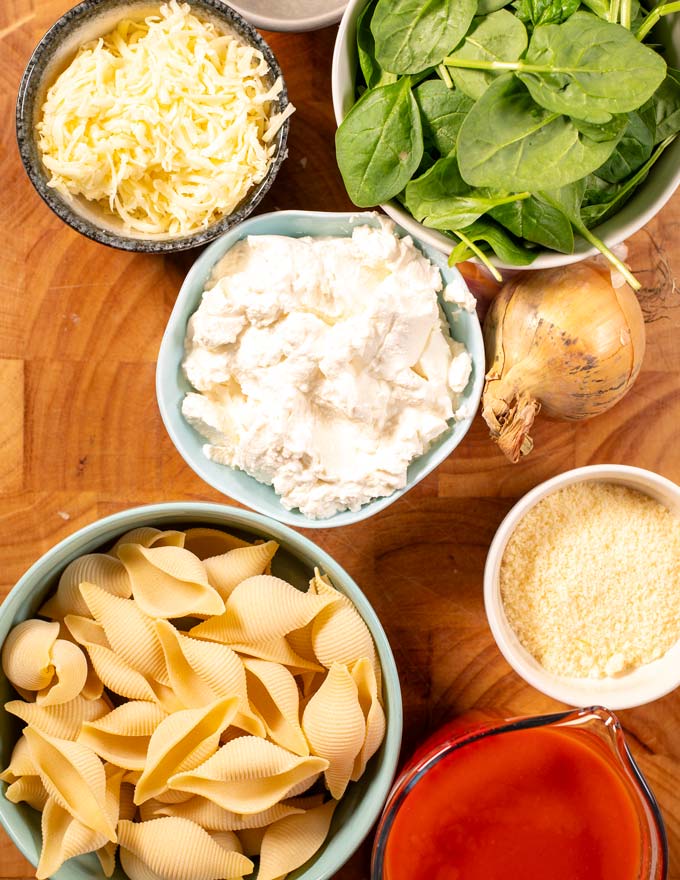 Ingredients needed to make Stuffed Shells are collected on a wooden board.