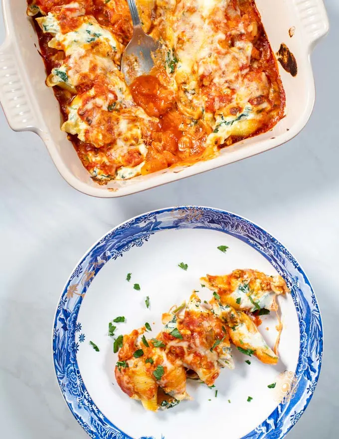 Top view of a serving of Stuffed Shells on a plate with the casserole dish in the background.