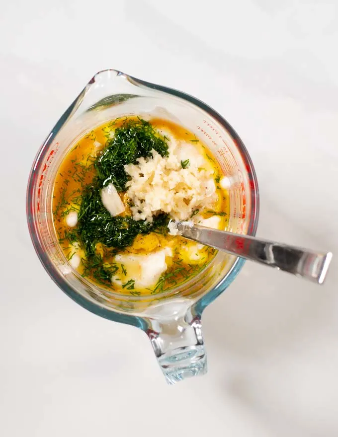 Top view of a small glass mixing bowl with ingredients for the Tuna Pasta Salad Dressing.