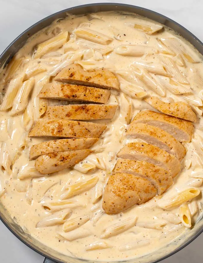 Slices Cajun chicken filets are given over the Alfredo Pasta.