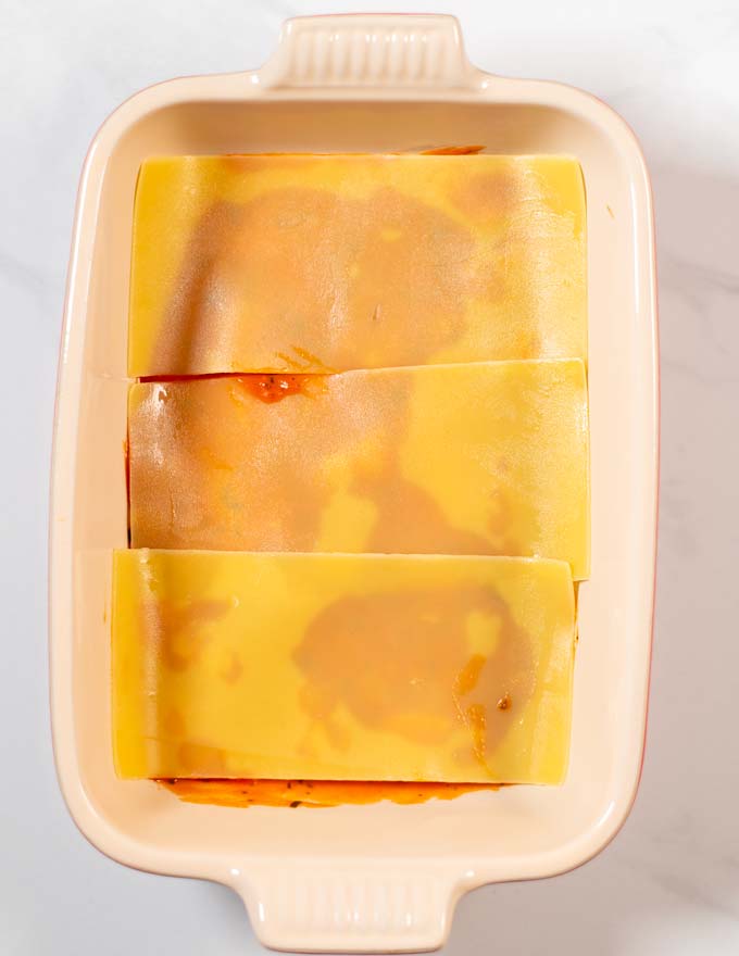 Step-by-step guide showing how precooked lasagna noodles are added to the casserole dish.