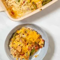 A portion of Texas Chicken Casserole is served on a plate with the casserole dish in the background.