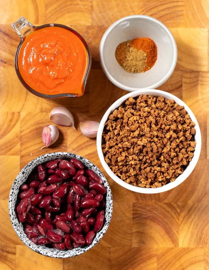 Ingredients needed to make Texas Chili Beans are collected on a wooden board.