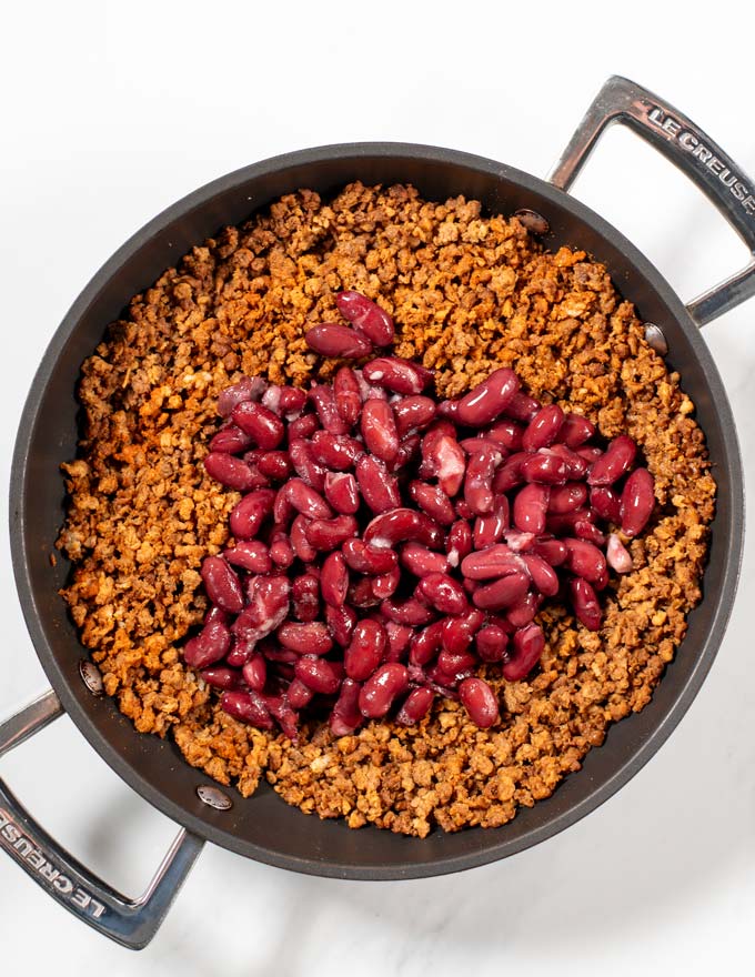 Drained kidney beans are given into the pan with ground beef.