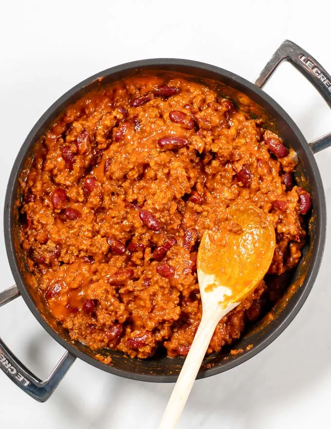 Top view of a pan with Texas Chili Beans with a wooden spoon.