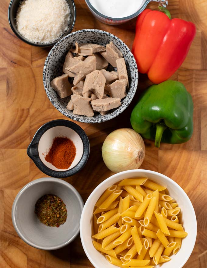 Ingredients needed to make vegan Rasta Pasta are collected on a wooden board.