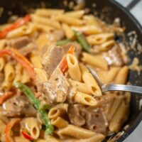 A large spoonful of vegan Rasta Pasta is lifted from the pan.