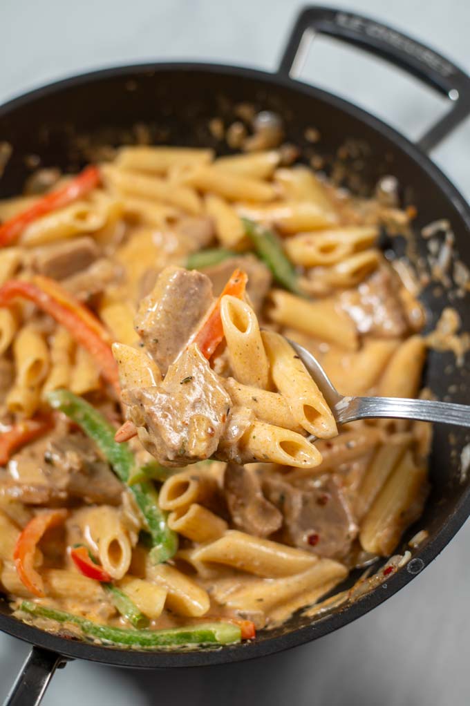 A large spoonful of vegan Rasta Pasta is lifted from the pan.