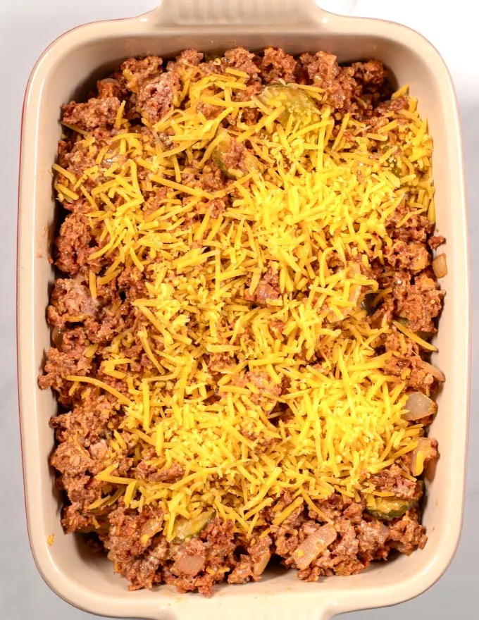 Keto Big Mac Casserole sprinkled with vegan cheddar cheese before baking.