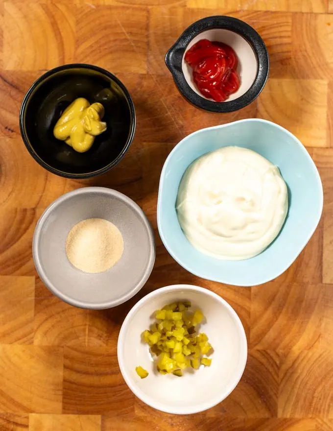 Ingredients needed to make homemade Keto Big Mac Sauce are collected on a board.