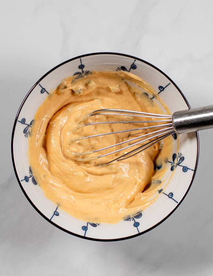 Top view of a mixing bowl and a wire whisk after mixing all ingredients.