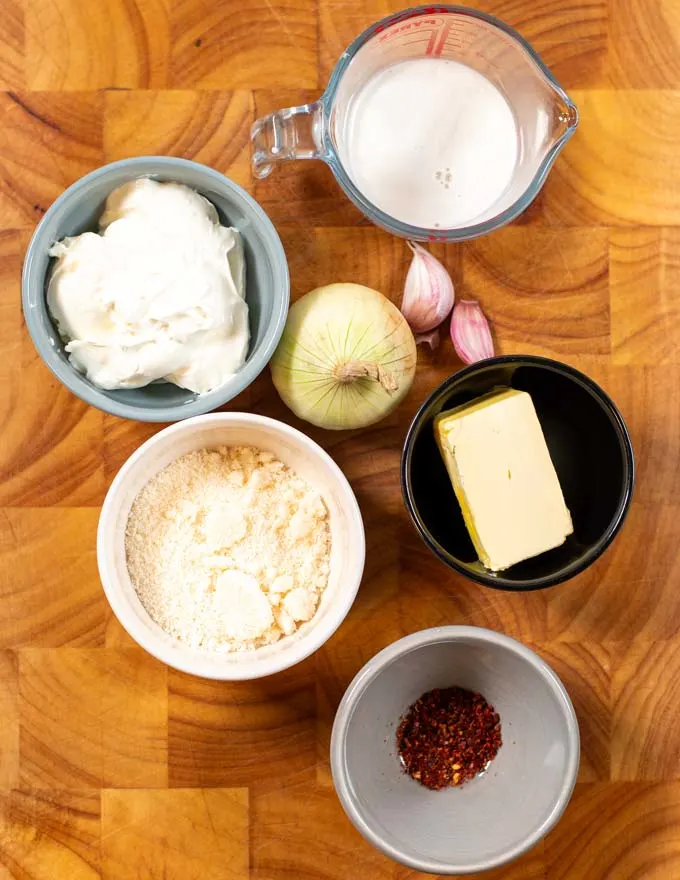Ingredients needed for making Spicy Alfredo Sauce are collected on a board.