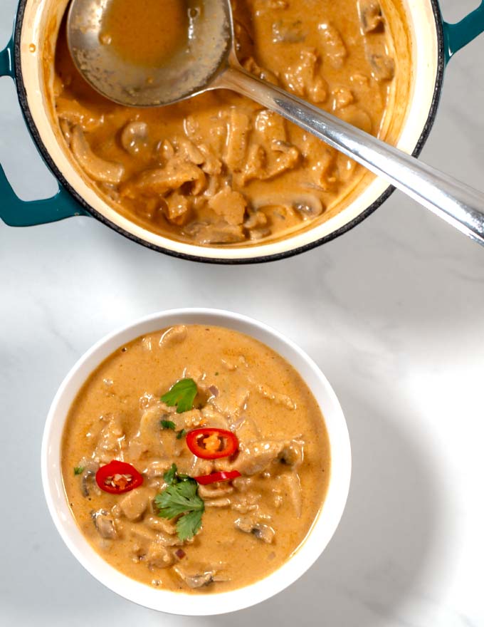 Top view of a serving bowl and the large pot of Tom Kha Soup.