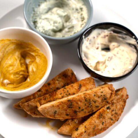 A serving of oven baked chicken tenders with dipping sauces.