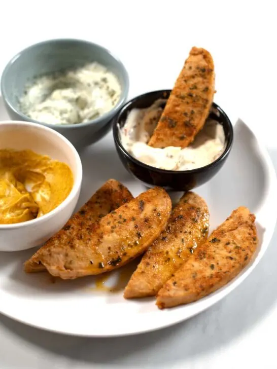 A chicken tender is dipped in sauce.