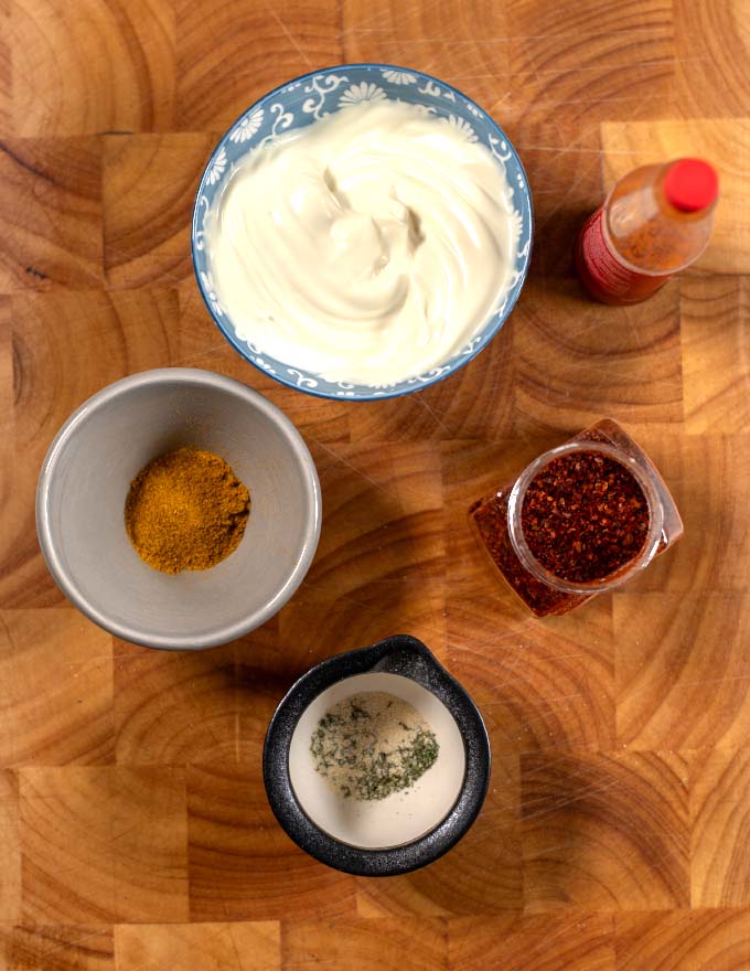 Ingredients needed to make Chicken Tenders Dipping Sauces are collected on a wooden board.