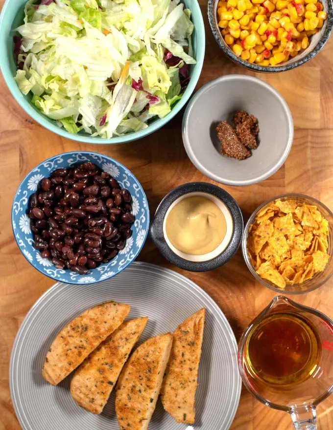 Ingredients needed to make Chicken Tenders Salad collected on a board. 