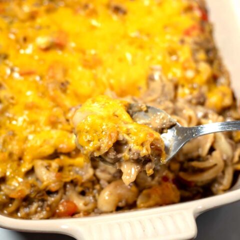 A spoon full of Mac and Cheese Casserole is lifted from the dish.