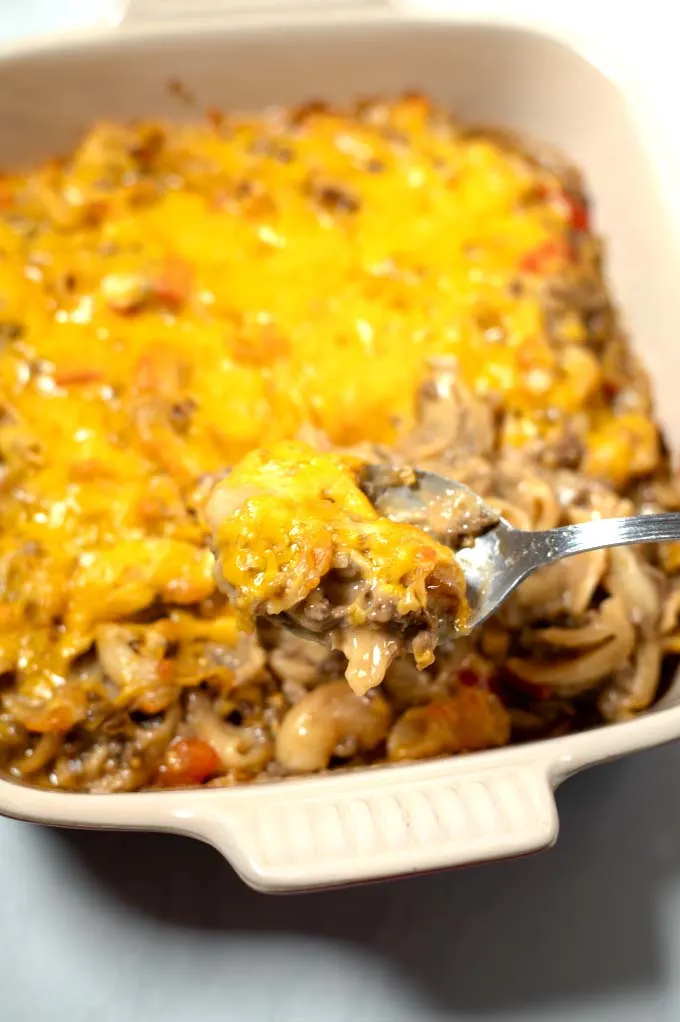 A spoon full of Mac and Cheese Casserole is lifted from the dish.
