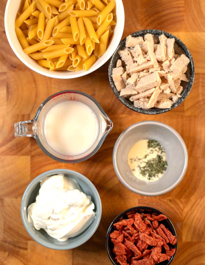 Ingredients needed to make Chicken Bacon Ranch Pasta on a board.