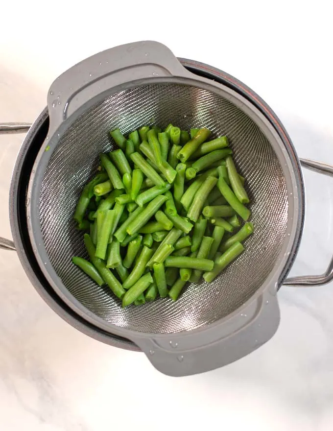 Pre-cooked green beans in a colander.