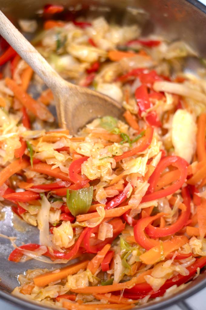 A wooden spoon stir the Jamaican Steamed Cabbage.