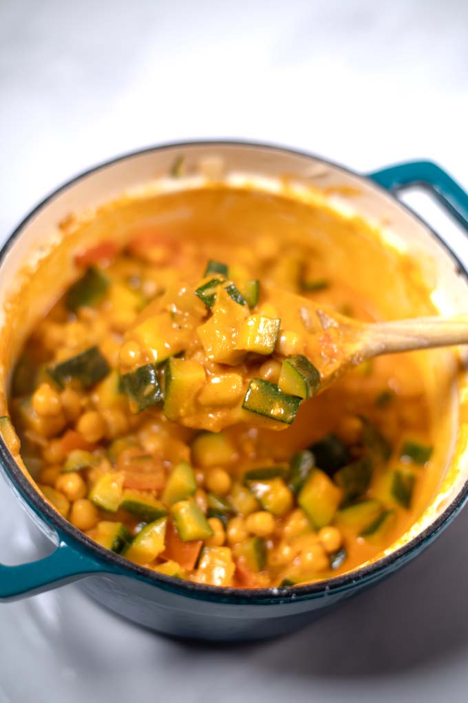 A spoonful of Zucchini Curry is lifted from the pot.